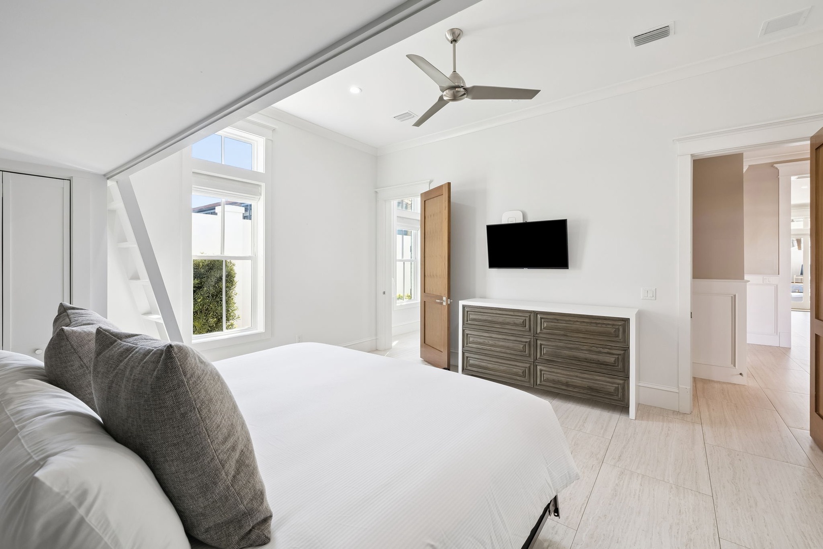 Your spacious master bedroom features crisp white linens, modern furnishings, and bright natural light streaming through large windows for ultimate comfort.