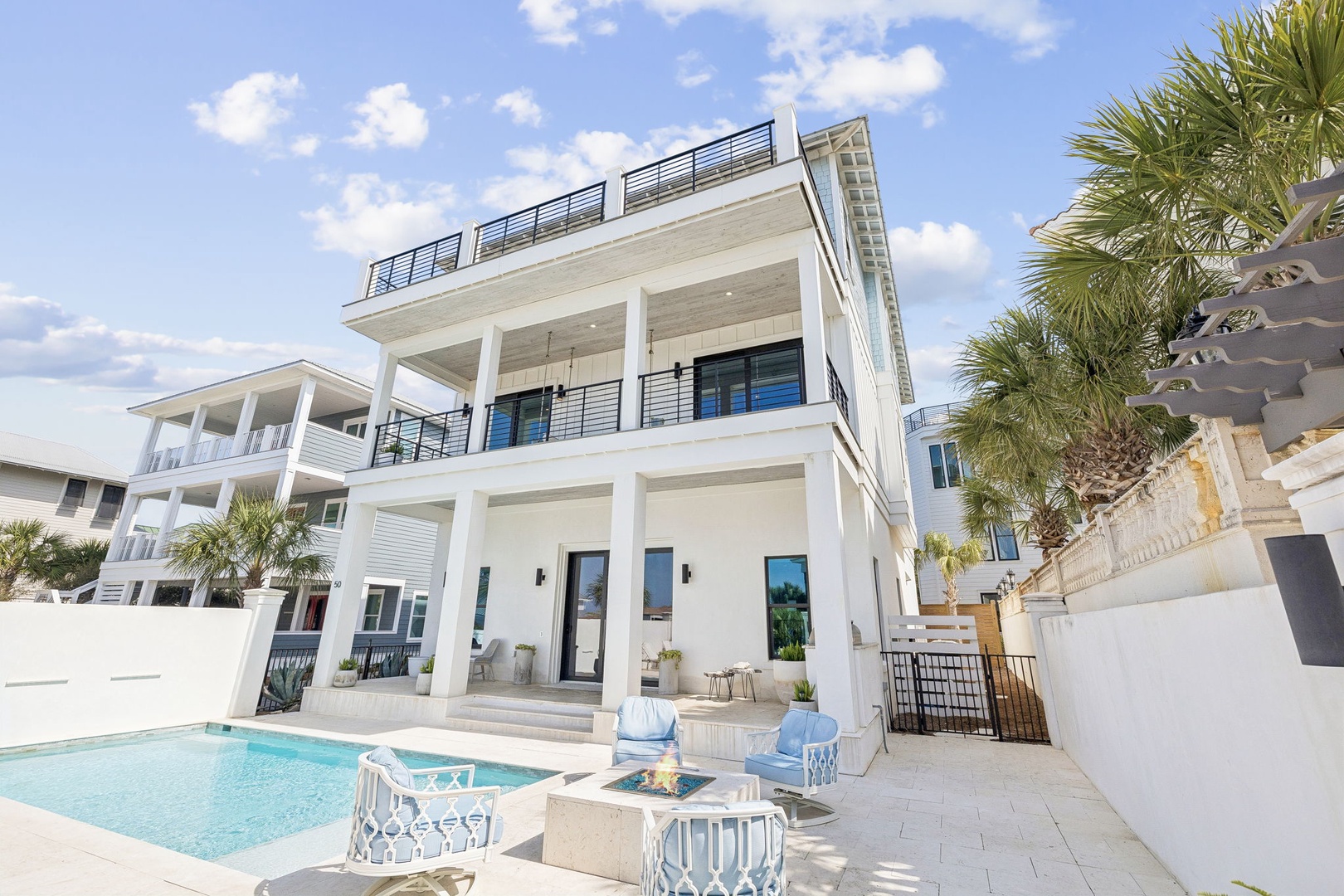Modern white coastal home featuring private pool, palm trees, and rooftop terrace in upscale beachside neighborhood.