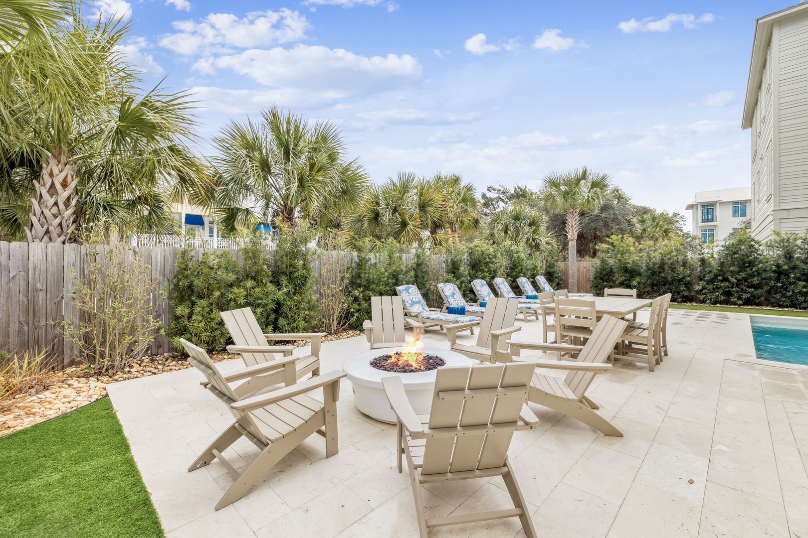 Gather around your private fire pit with comfortable Adirondack chairs, surrounded by tropical palms and modern outdoor amenities for perfect evening relaxation.