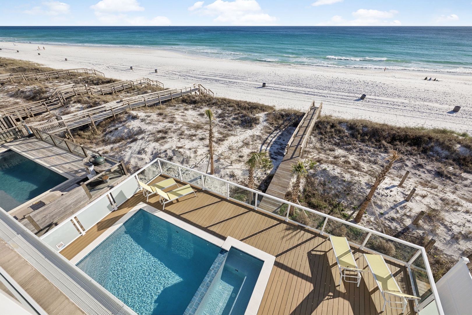Aerial view of beachfront property featuring private pools and direct beach access via elevated wooden walkways.