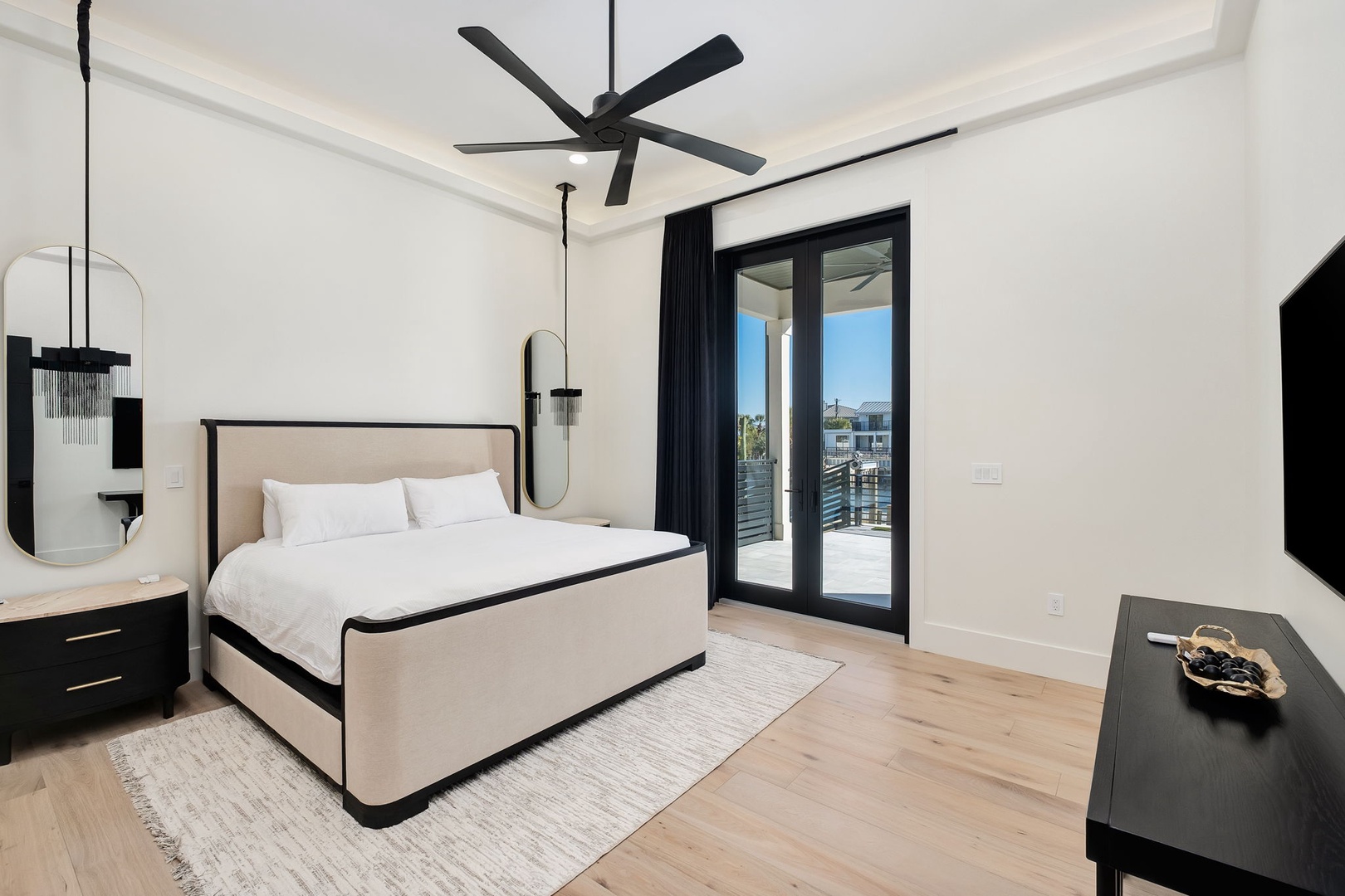 Sink into crisp white linens in your modern bedroom, where natural light streams through glass doors opening to your private balcony.