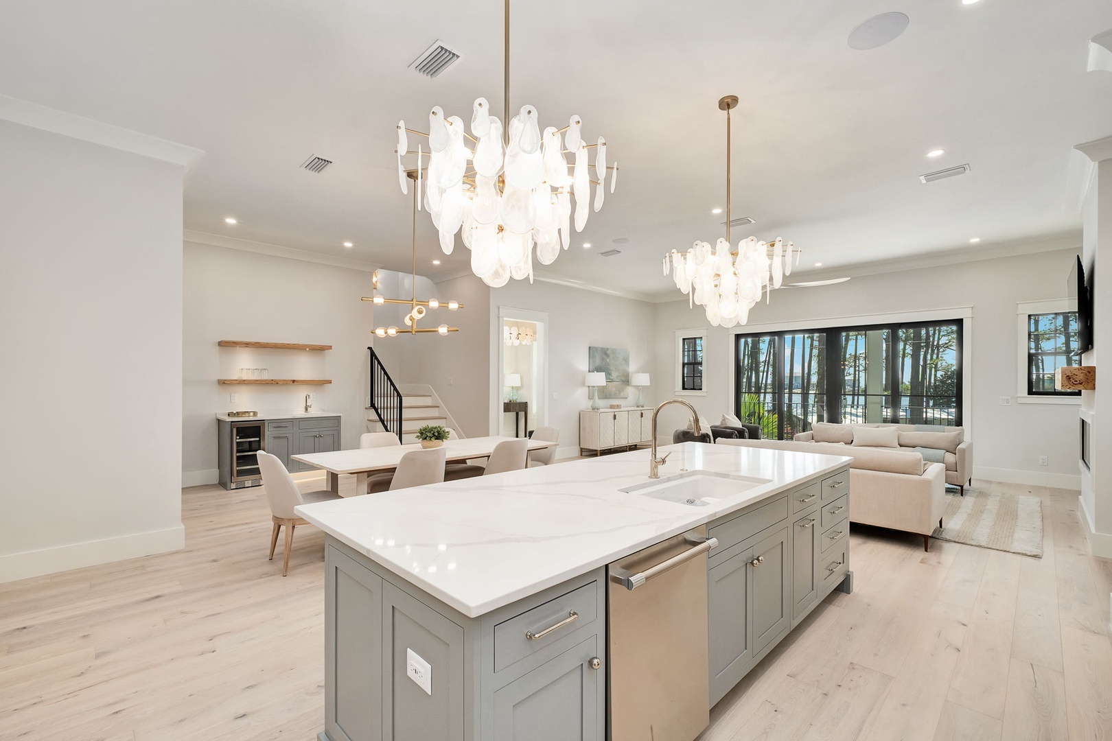 Luxury open-plan living awaits with a stunning gourmet kitchen island, elegant chandeliers, and seamless flow to your comfortable lounge area.