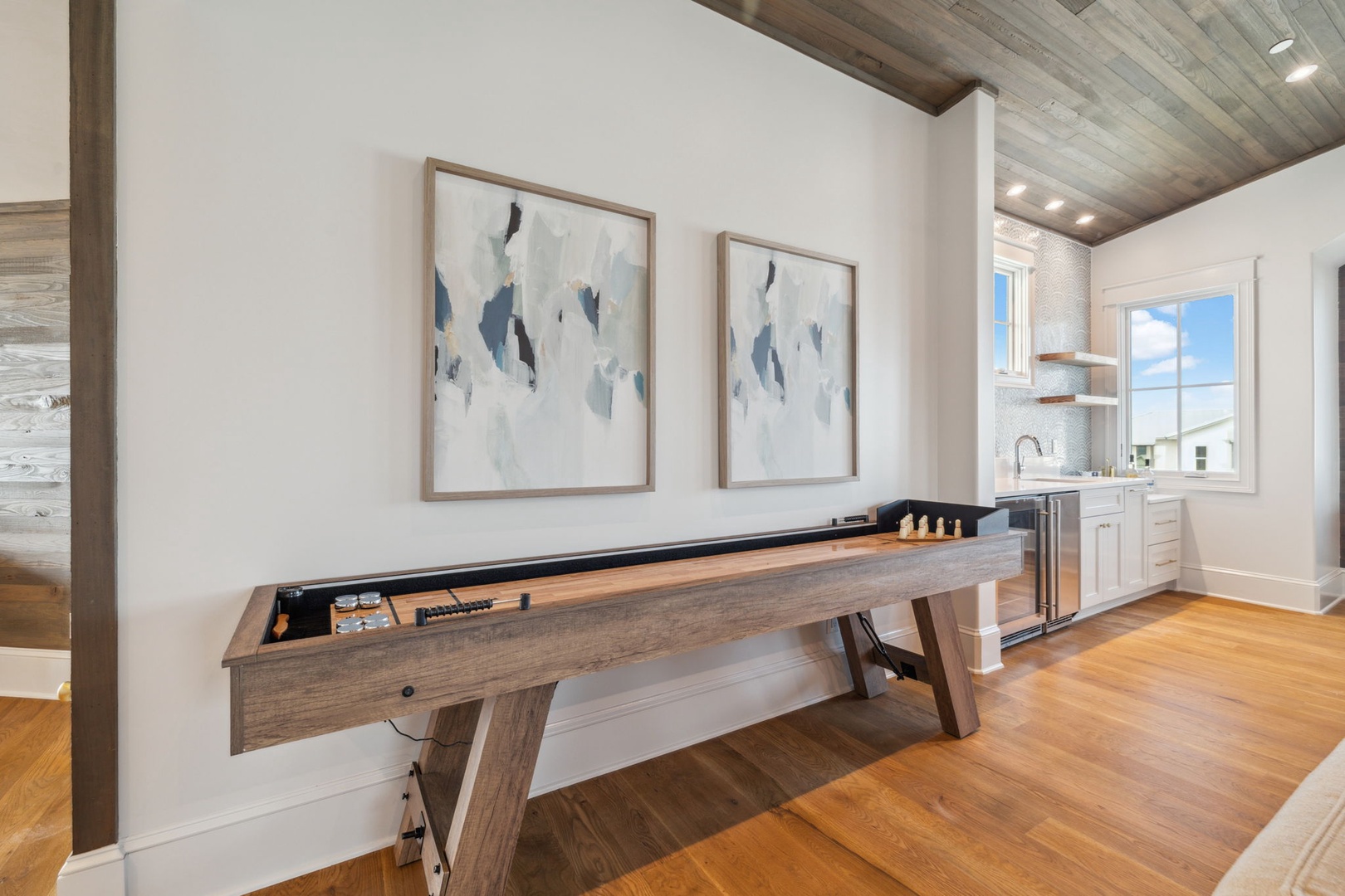 Your private game room awaits with a sleek shuffleboard table, reclaimed wood ceilings, and a convenient kitchenette for effortless entertaining.