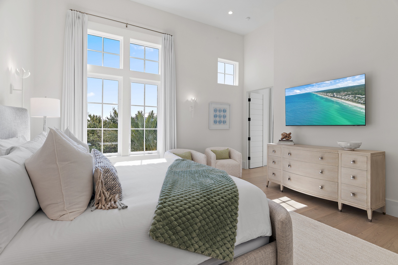Sink into coastal comfort in your bright bedroom, where soft linens meet serene sea views through tall windows and plush textures invite restful nights.