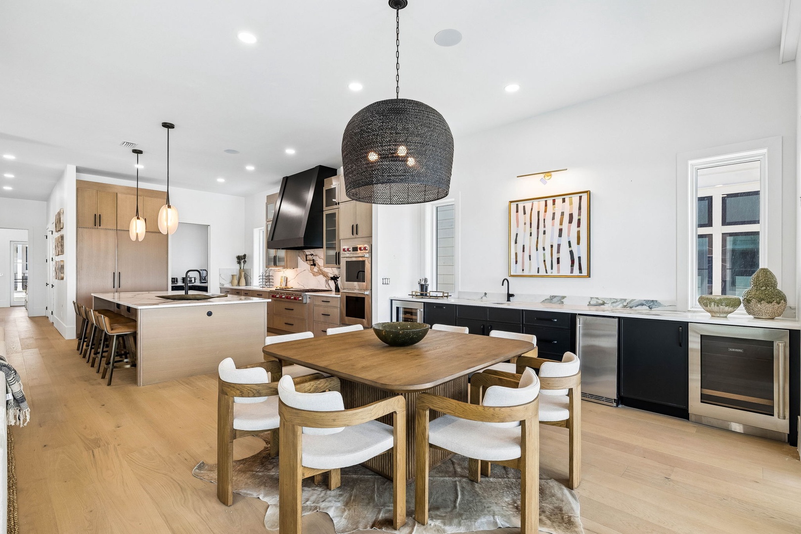 Step into a beautifully designed open-concept space where you can prepare meals in a sleek, fully equipped kitchen, share stories around the warm wood dining table, and unwind in light-filled comfort.