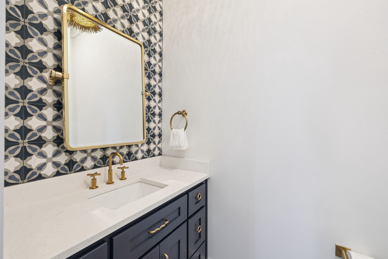 Your powder room dazzles with bold patterned tiles and gleaming brass fixtures that catch the light beautifully.