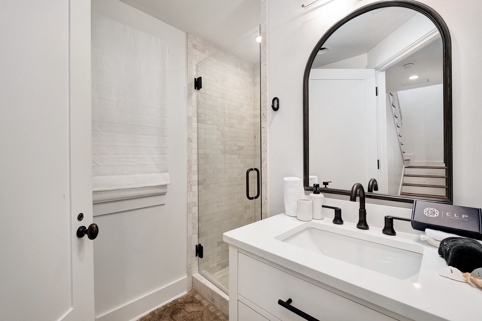 Step into your elegant bathroom featuring pristine subway tile shower, sleek black fixtures, and thoughtful amenities for your comfort.