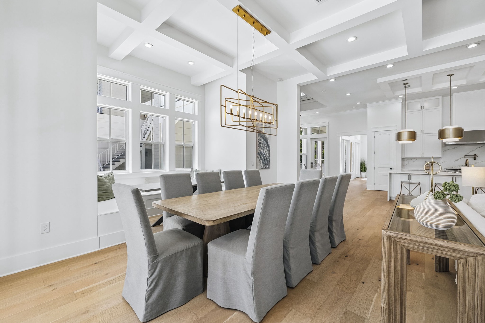 Host elegant gatherings at this sophisticated dining table, flooded with natural light from tall windows. The chandelier and coffered ceiling create an upscale atmosphere perfect for entertaining.