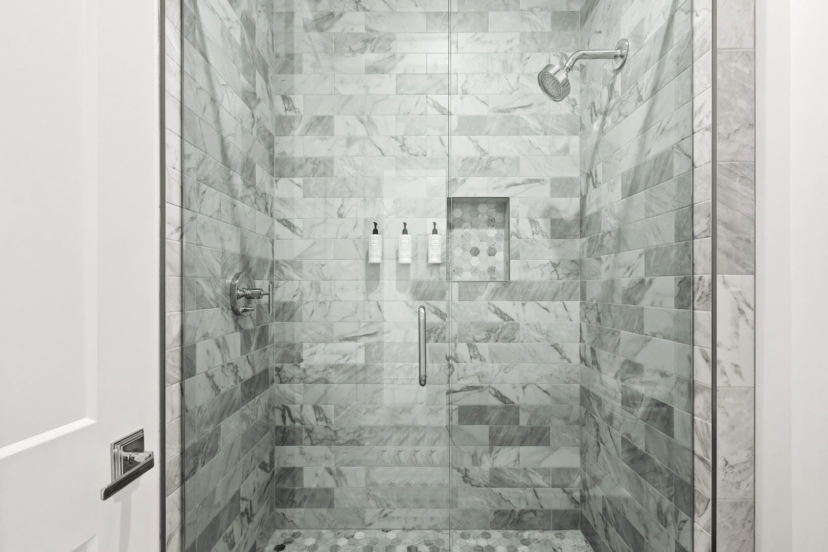 Step into your spa-inspired walk-in shower, wrapped in elegant marble tile with a rainfall showerhead overhead and premium toiletries within easy reach.