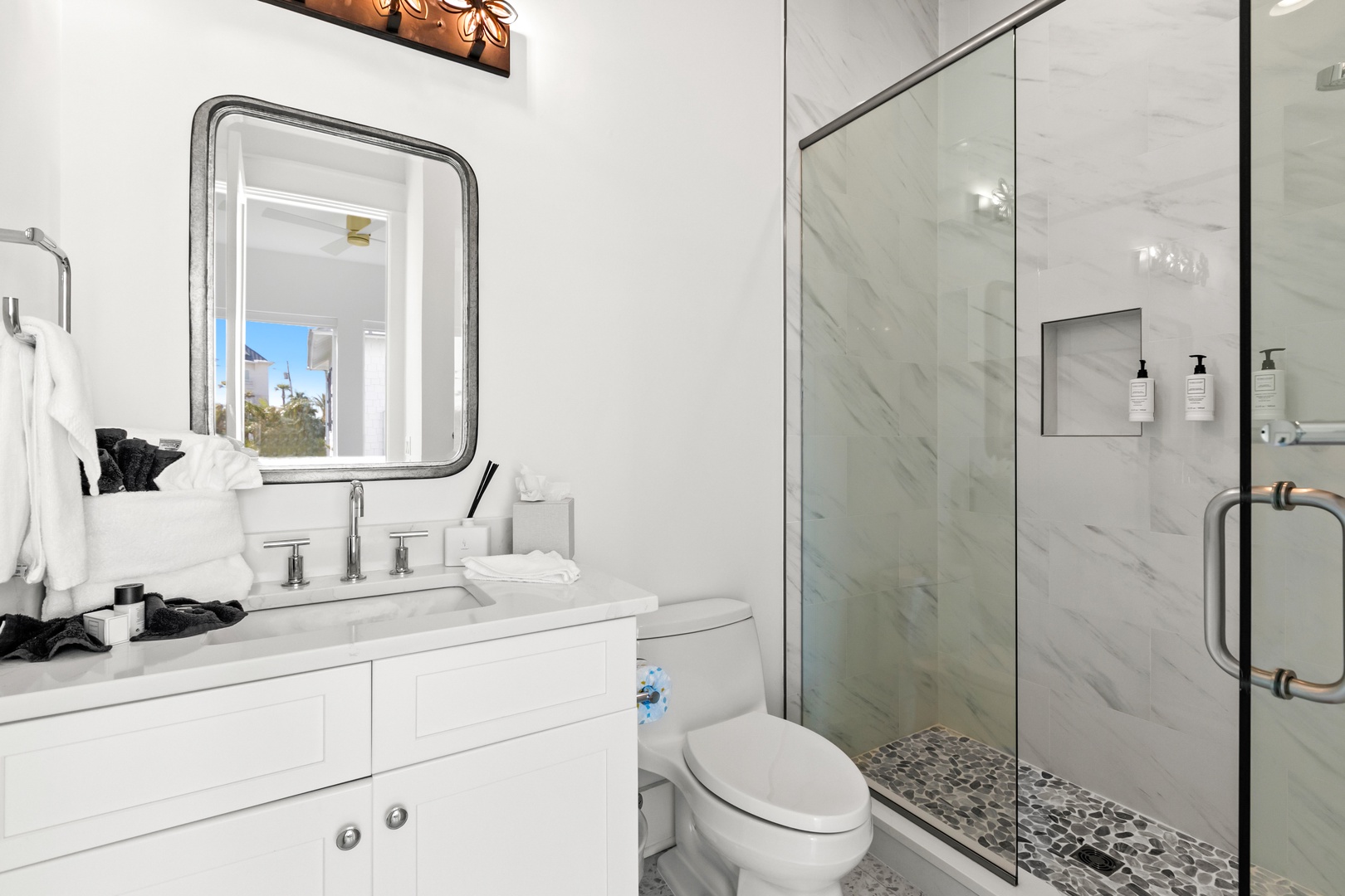 Freshen up in this bright, modern bathroom featuring gleaming marble, a spacious walk-in shower, and plush towels ready for your arrival.