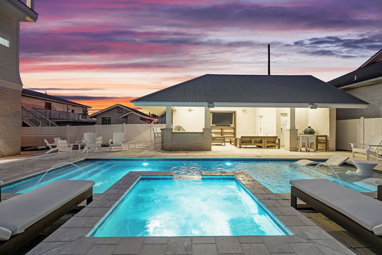 Stunning outdoor pool area with hot tub captures dramatic sunset colors across the sky, creating a picturesque evening atmosphere.