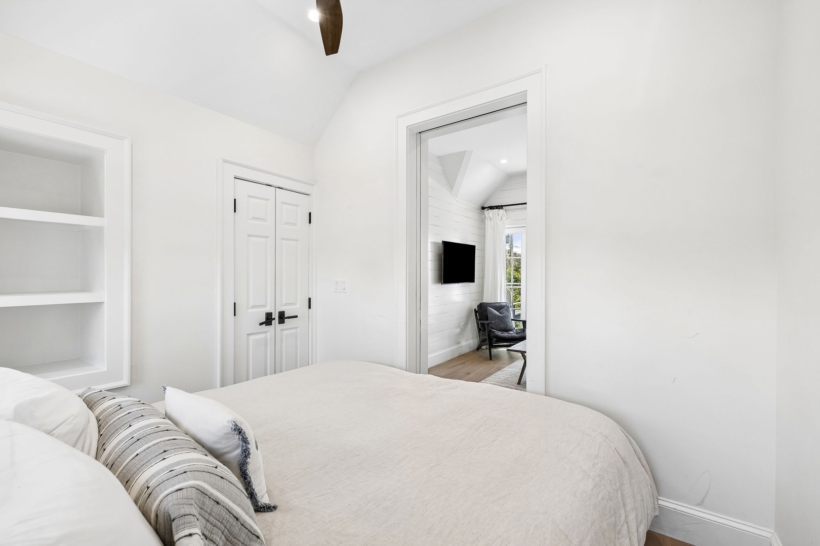 Sink into crisp linens and unwind in your serene bedroom retreat, where vaulted ceilings and built-in shelving create a peaceful haven for restful nights.