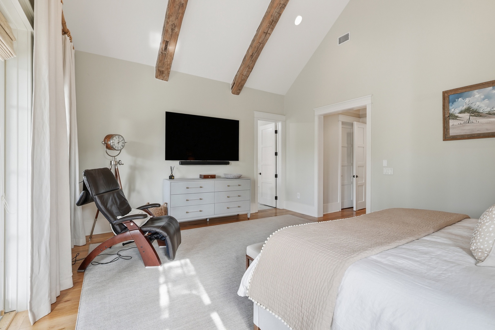 Drift off in your serene bedroom featuring soaring vaulted ceilings with rustic wood beams, a plush bed, and a relaxing massage chair for unwinding after your adventures.