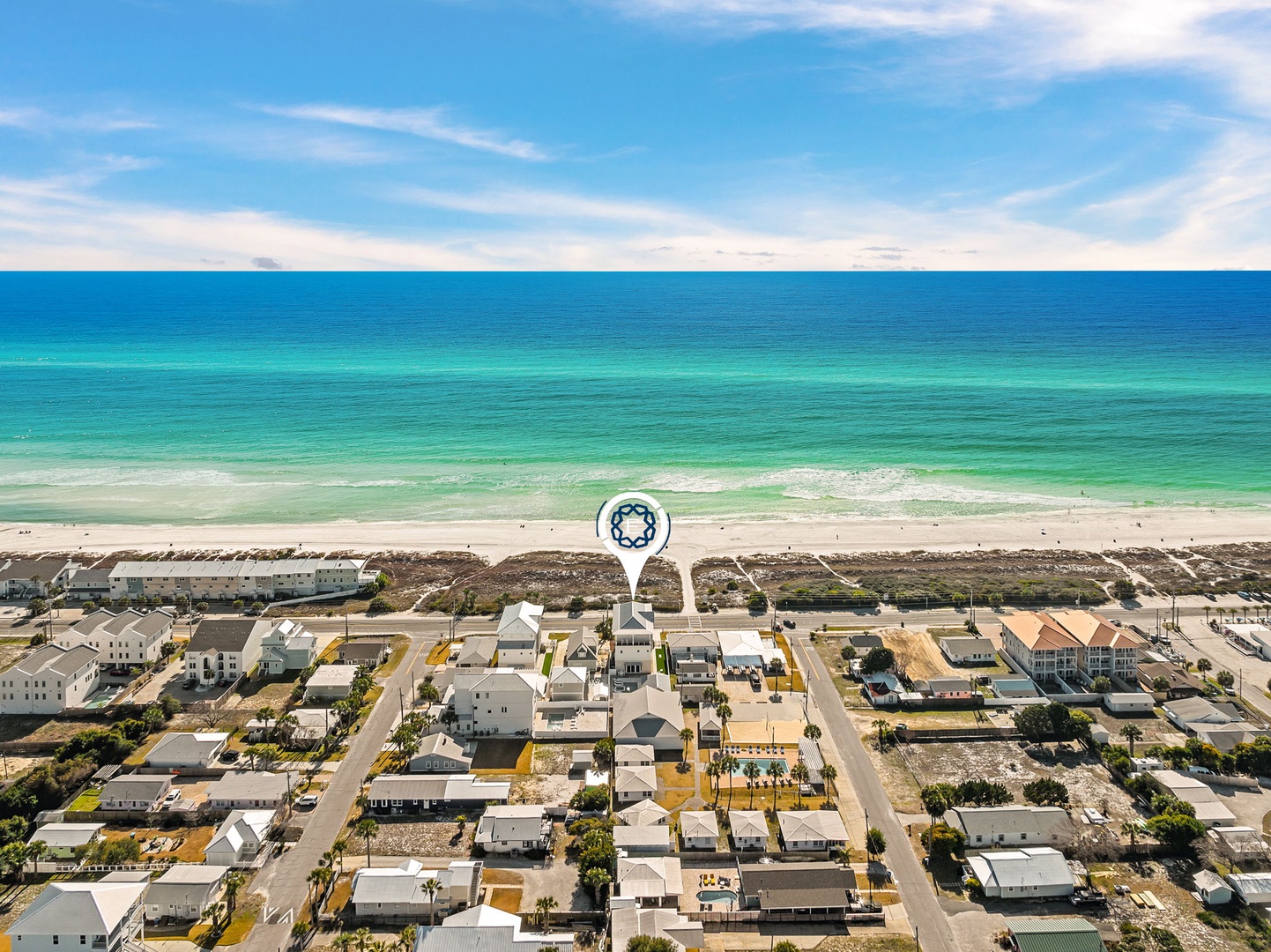 Aerial view of beachfront neighborhood with pristine turquoise waters and white sand beach just steps away from residential area.