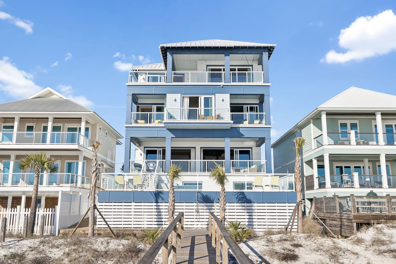 Modern beachfront property with multiple decks and direct beach access via wooden walkway.