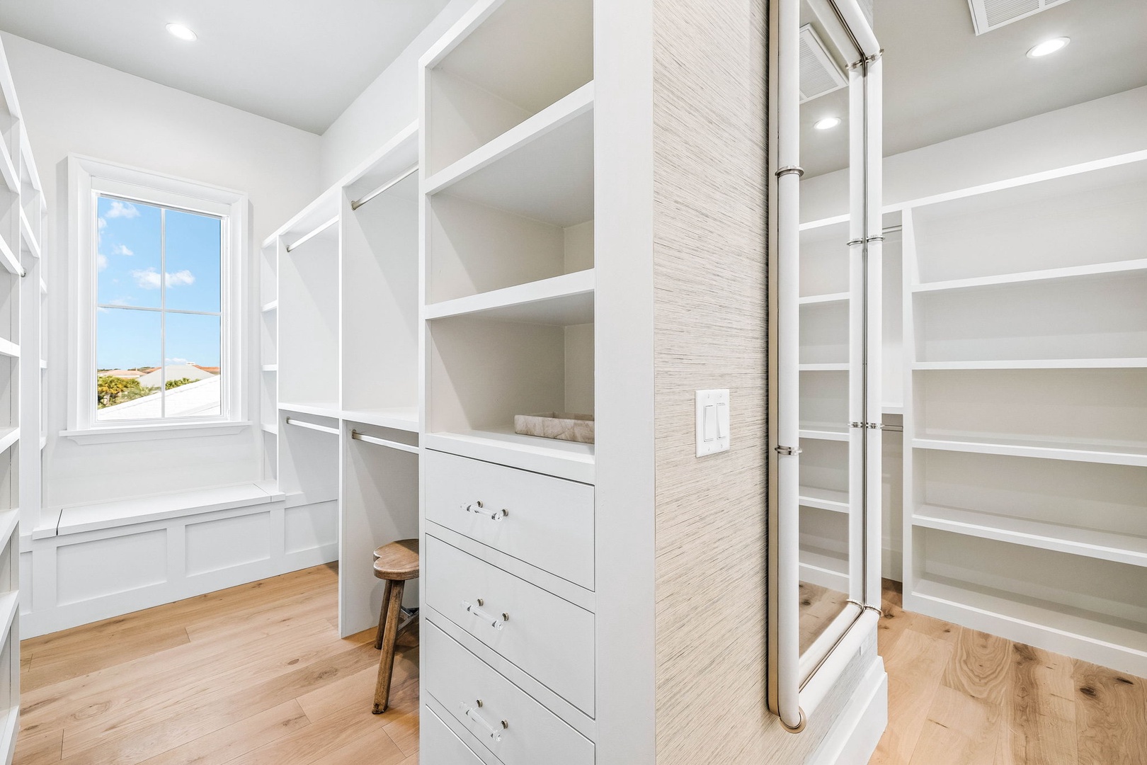 Step into your spacious walk-in closet with custom built-in shelving and drawers—perfect for organizing your wardrobe in style. Natural light from the window brightens the space while you plan your day in comfort.
