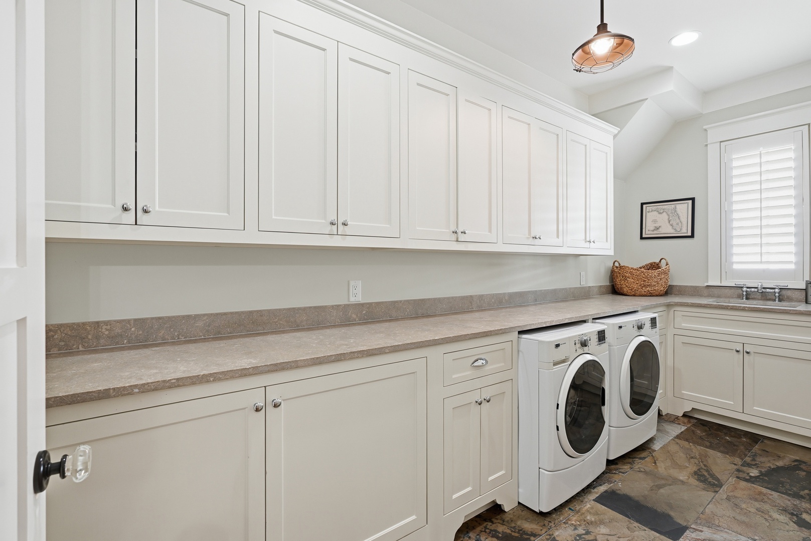 This bright laundry room offers generous storage with floor-to-ceiling white cabinetry and stylish pendant lighting to make chores a breeze.