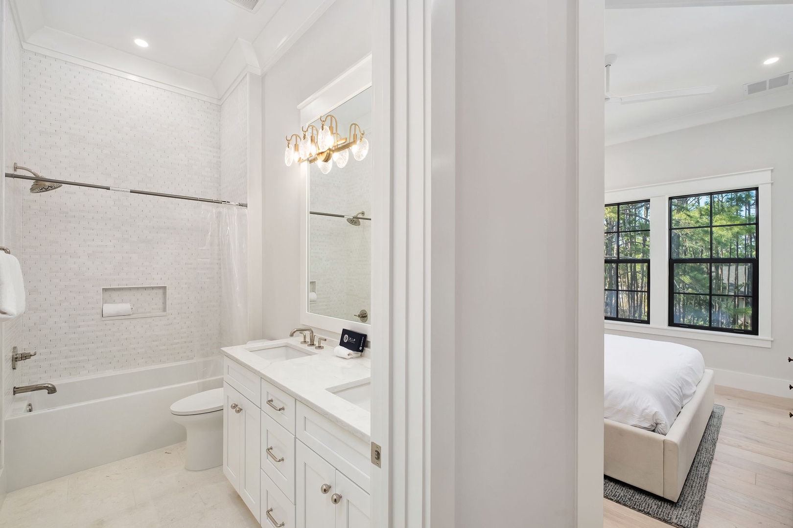 Your pristine ensuite bathroom features elegant white tile work, a luxurious tub-shower combo, and stylish gold accents for pure relaxation.