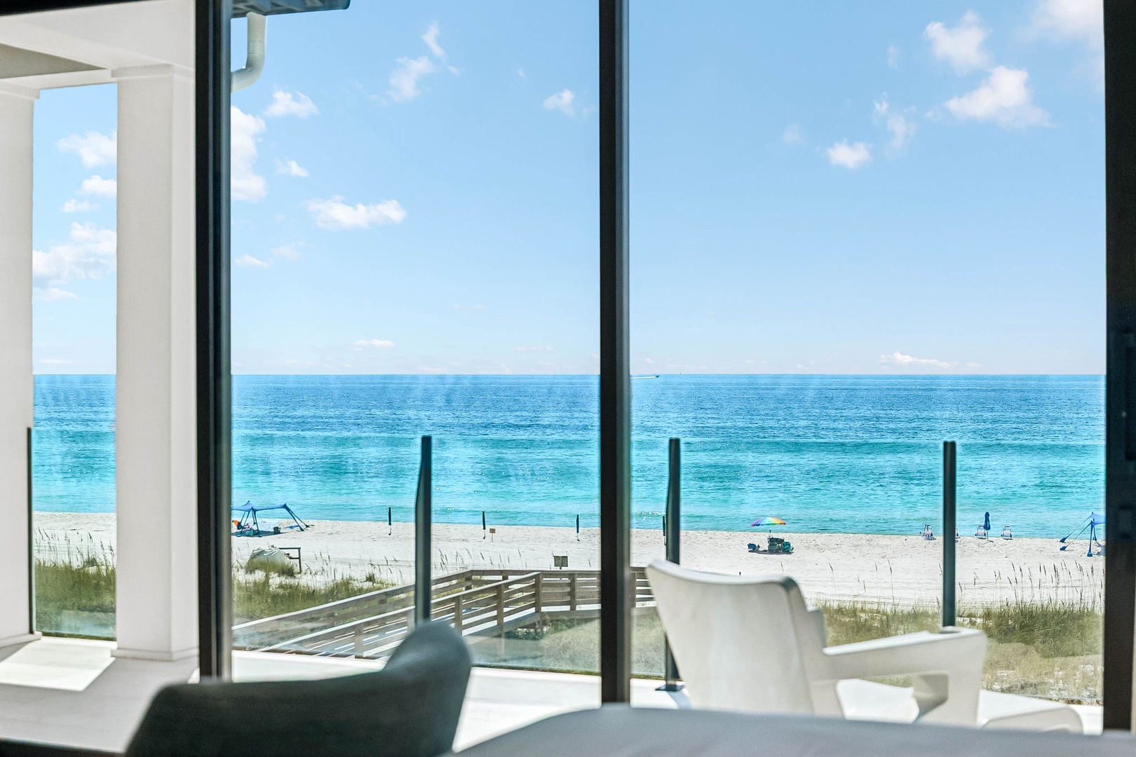 Step into your bright, open living space and let your eyes drift through floor-to-ceiling windows straight to the turquoise sea and sandy shore beyond—your own front-row seat to paradise.