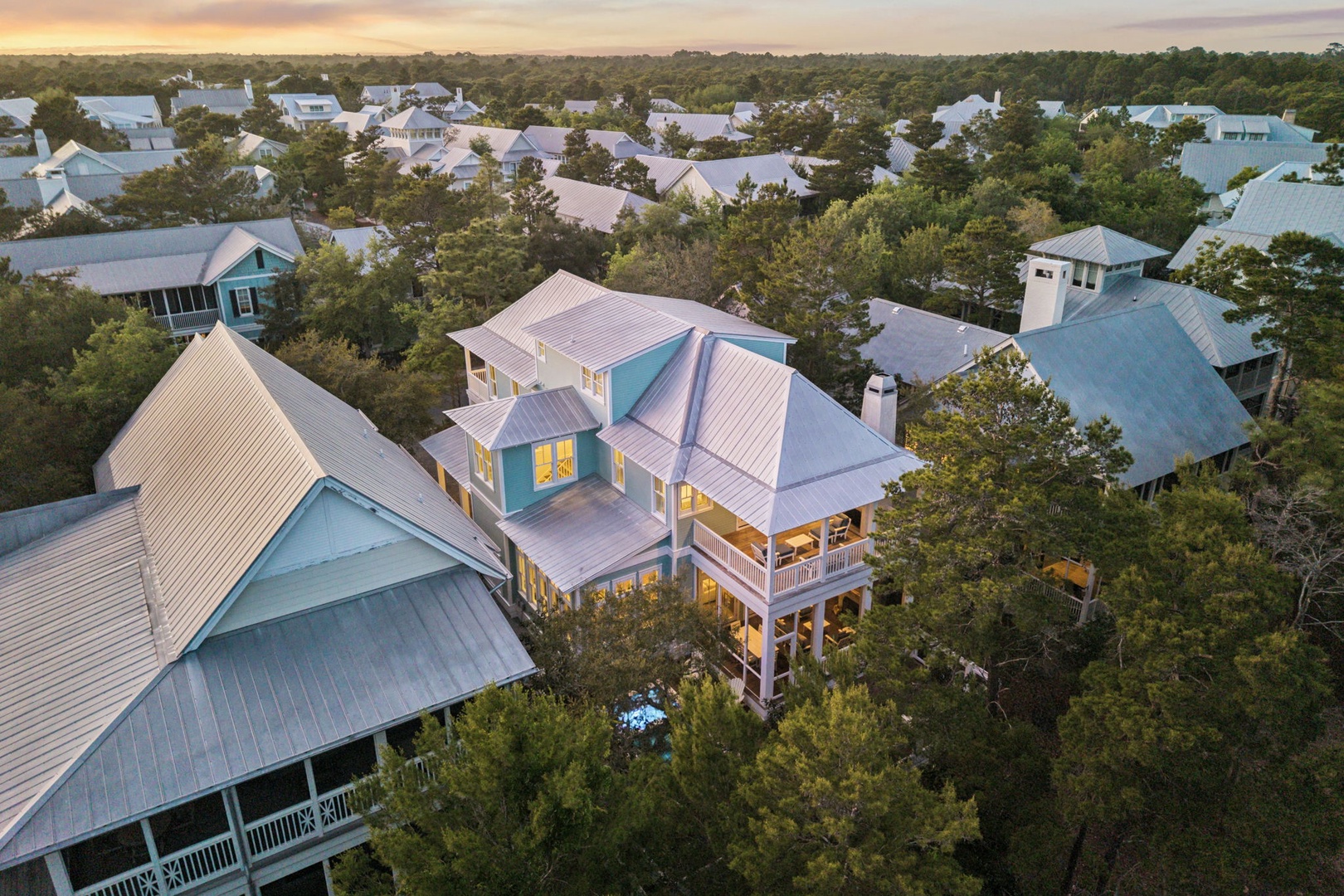 Stunning aerial view of coastal vacation homes nestled among lush trees, capturing the golden hour glow over this peaceful residential community.