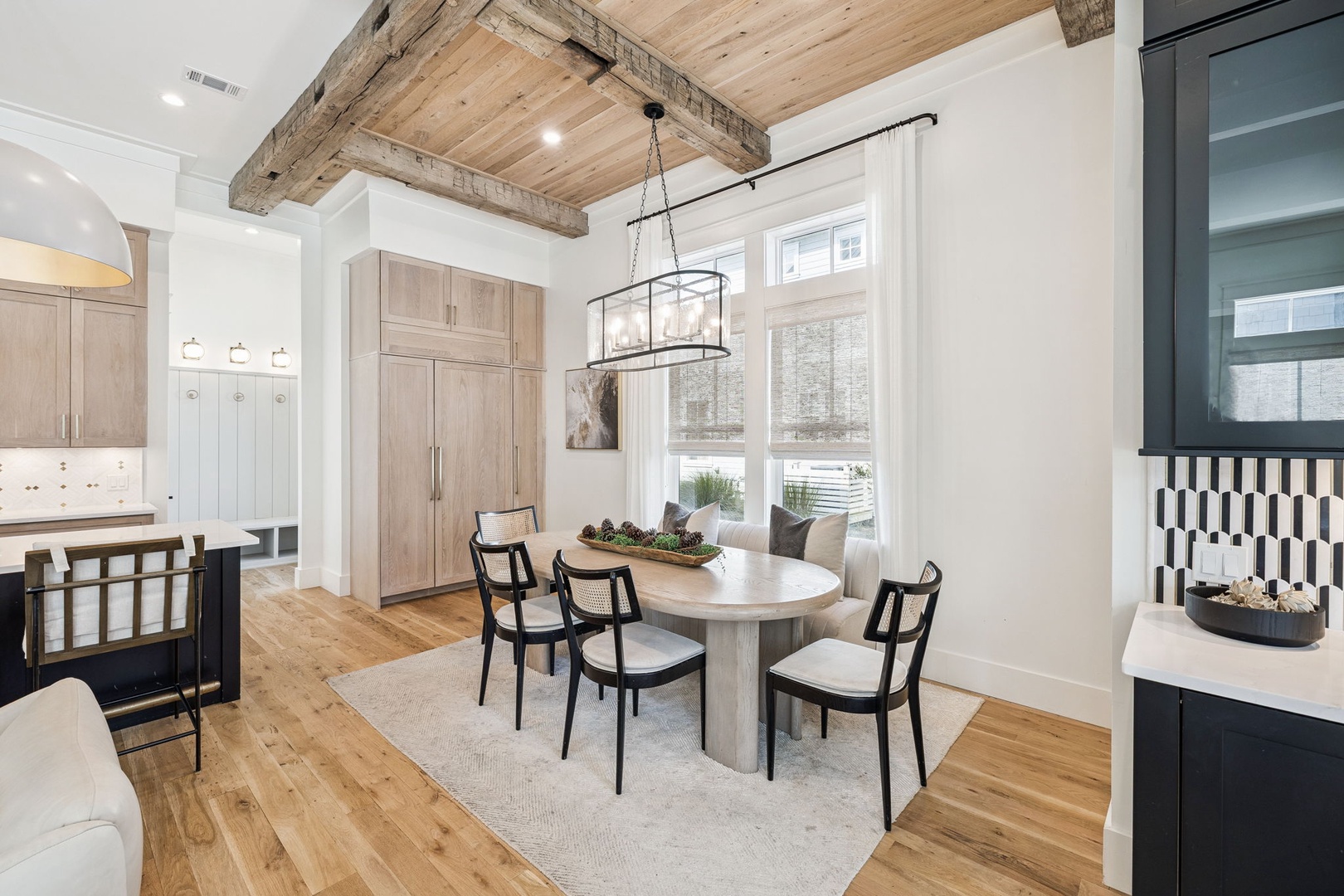 Gather around this elegant round dining table beneath rustic exposed beams, where your morning coffee feels extra special in this bright, sophisticated space.