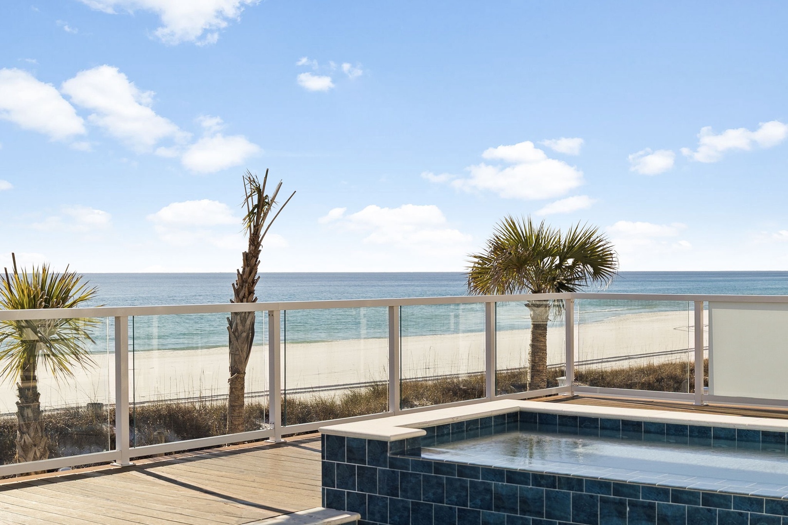 Soak in your private hot tub while gazing at pristine ocean views through sleek glass railings on this stunning beachfront deck.