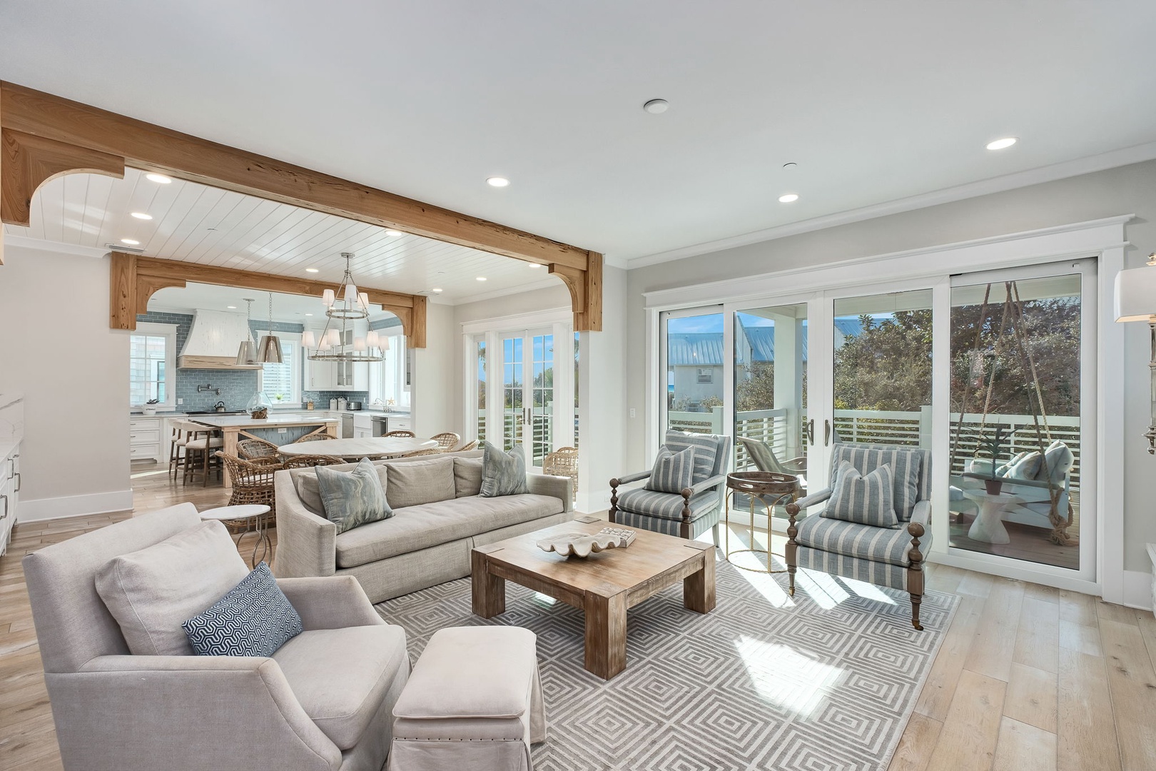 Sink into plush sofas in your open-concept living space, where natural light streams through expansive windows and wooden beams frame your kitchen.