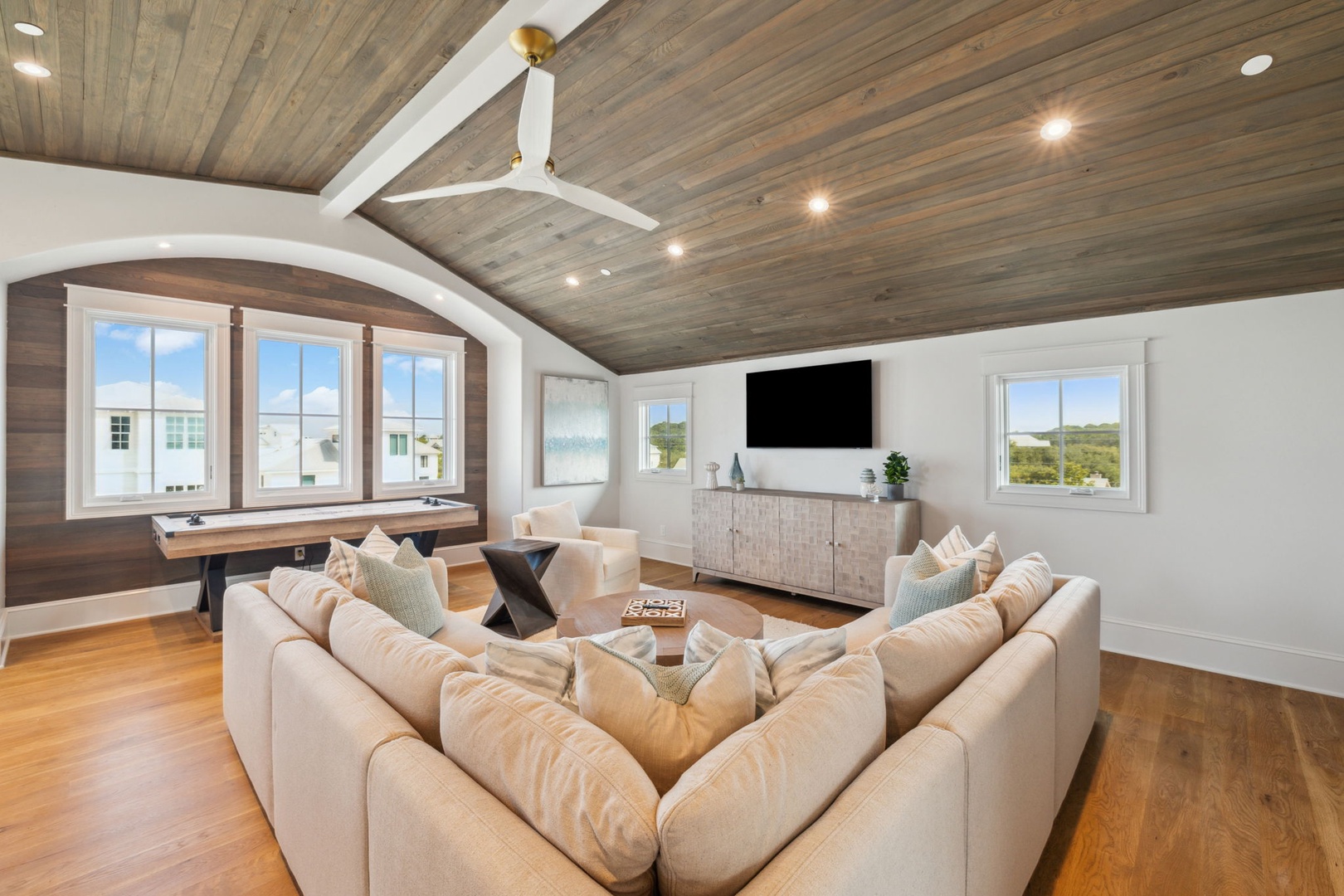 Sink into plush sofas under soaring wood-paneled ceilings. Stream your favorite shows or simply unwind in this inviting space, where natural light and modern comfort meet.
