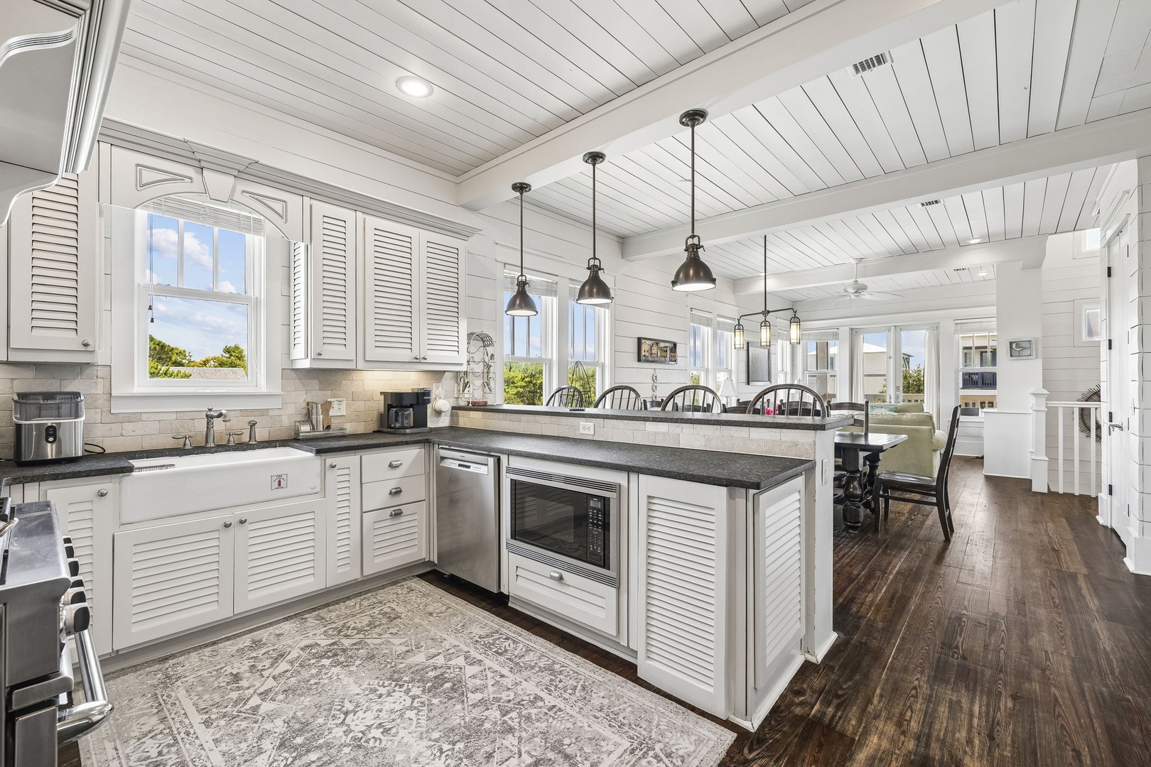 Bright open-concept kitchen featuring stainless steel appliances, gorgeous countertops, and natural light from windows overlooking lush greenery.