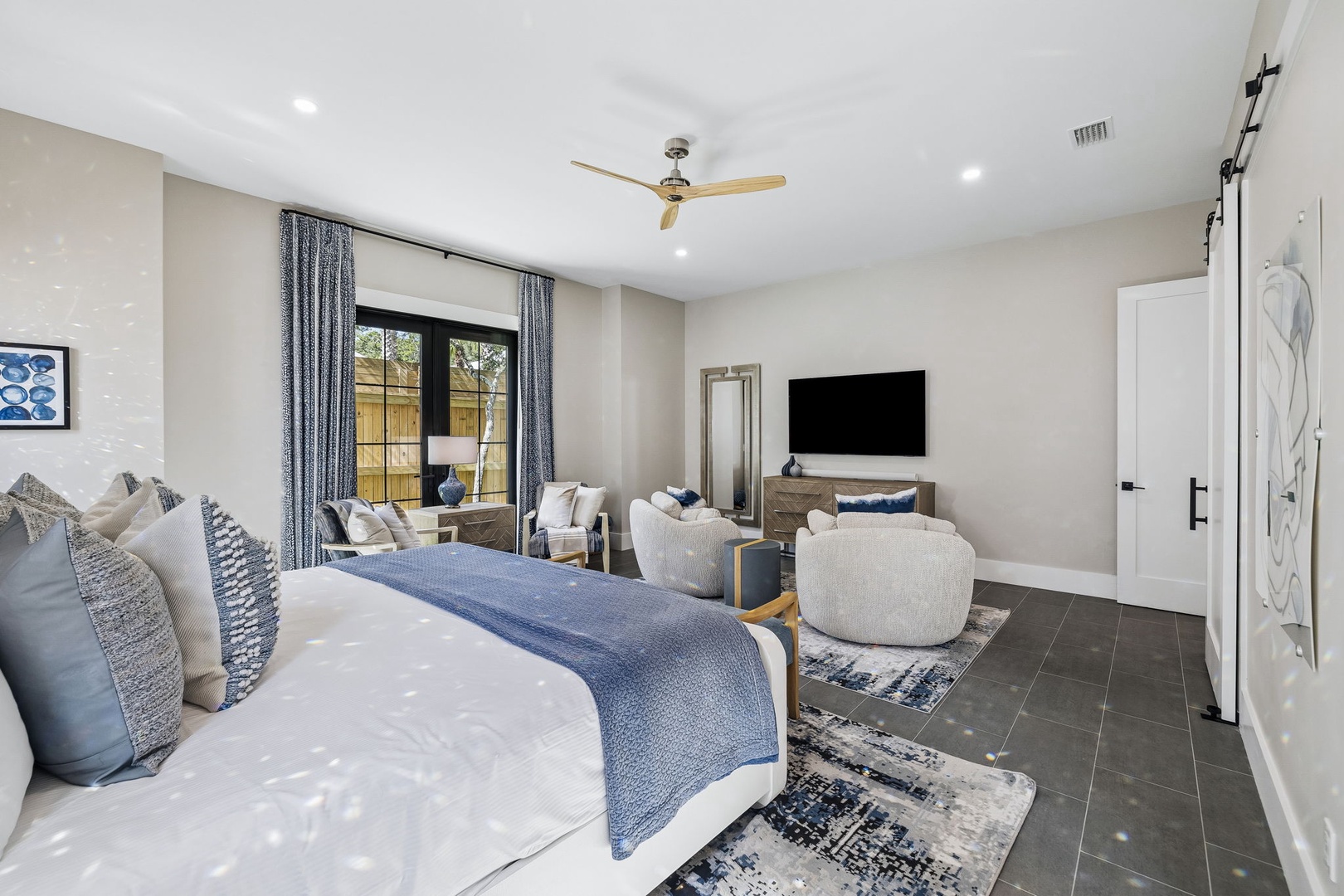 Relax in your spacious retreat with a plush king bed, cozy sitting area, and modern entertainment setup. The ceiling fan and natural light create an inviting atmosphere where you can truly unwind.