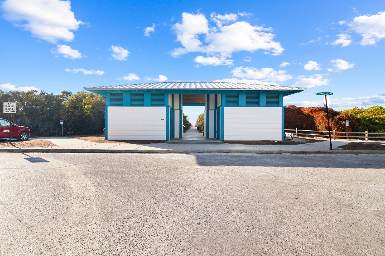 Modern beachside facility with turquoise accents set against bright blue skies and autumn foliage.