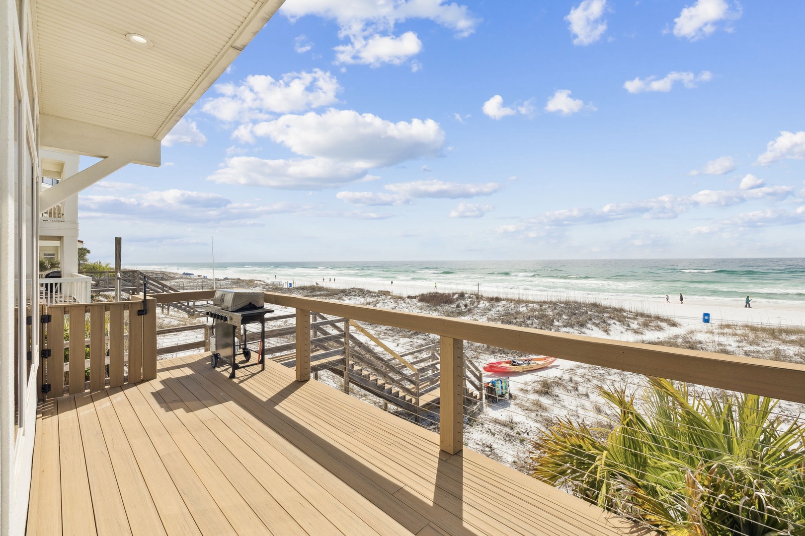 Spacious beachfront deck with BBQ grill offering stunning ocean views and direct beach access.