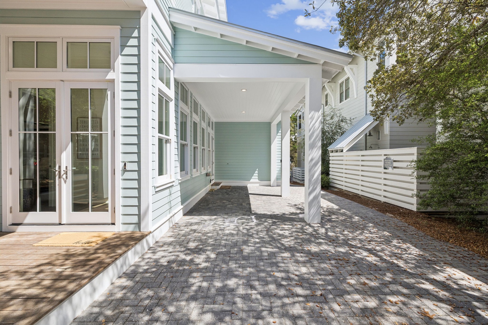 Modern coastal-style property featuring covered parking and elegant architectural details in a peaceful residential setting.