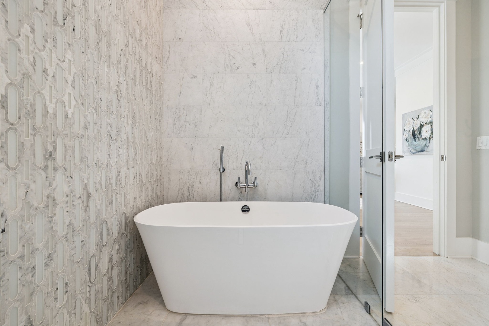 Indulge in your own private spa retreat with this elegant freestanding tub, surrounded by luxurious marble and designer tile.