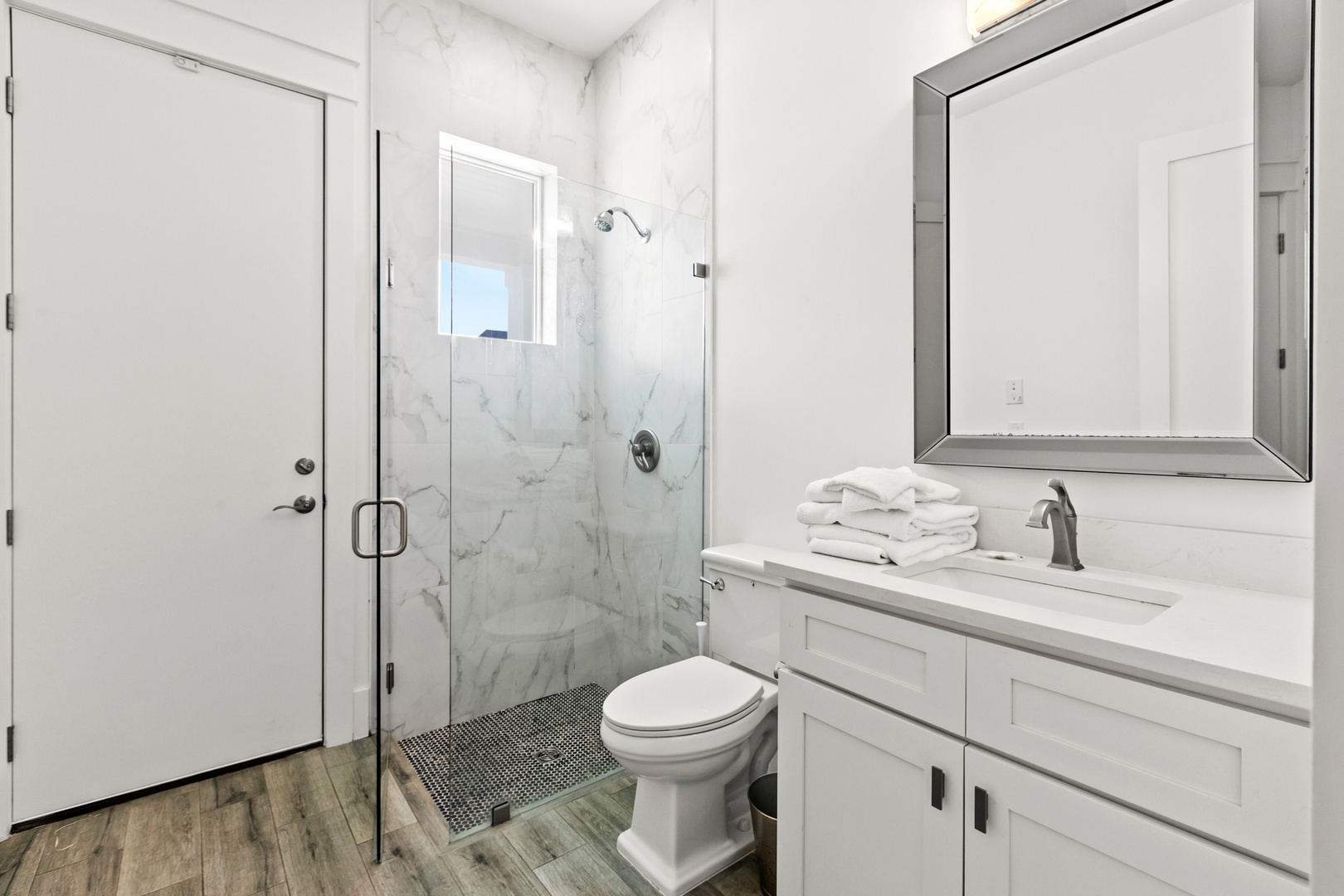 Step into your pristine marble-accented bathroom with a spacious glass-enclosed shower and fresh towels awaiting your arrival.