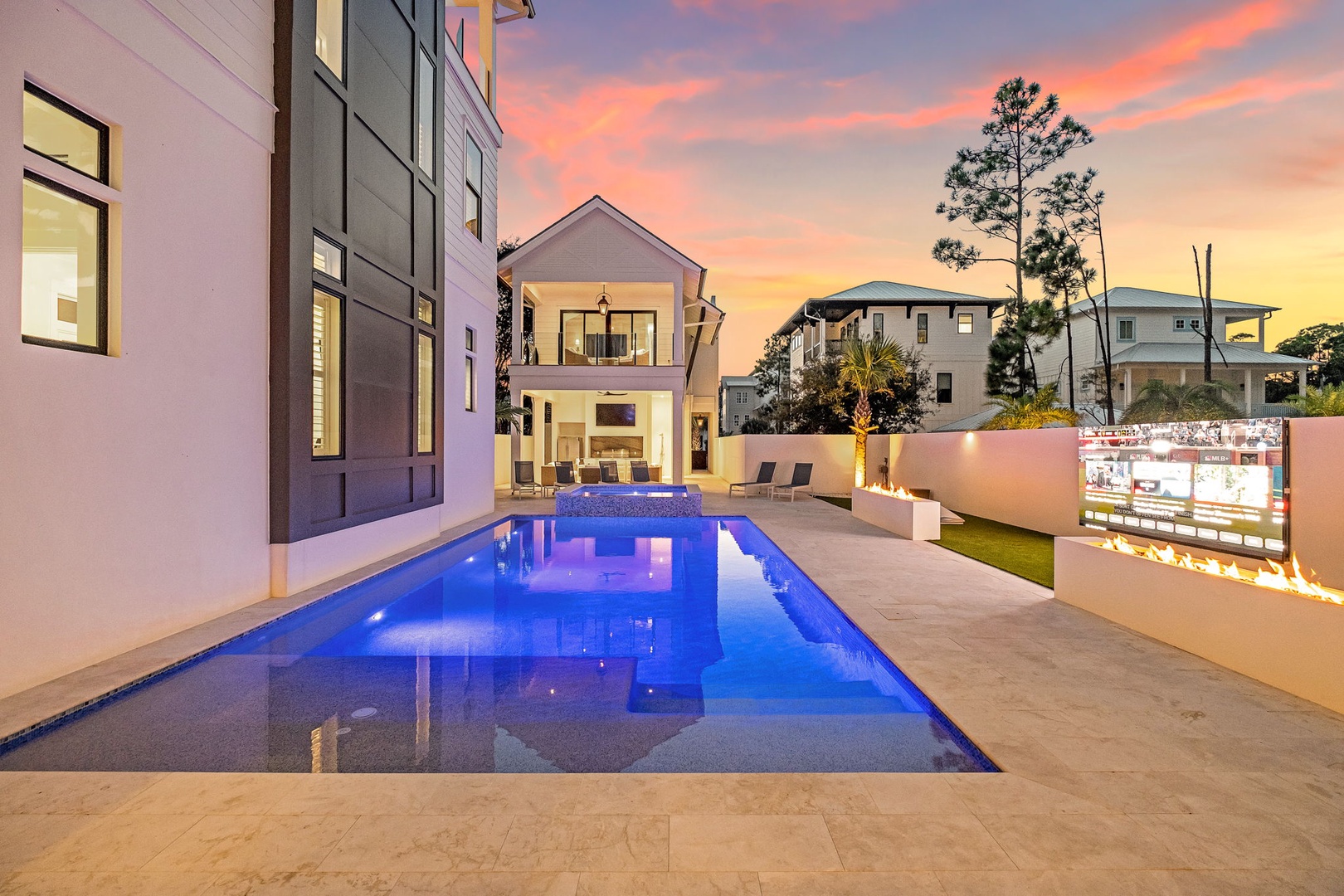 Modern vacation home with private pool surrounded by contemporary architecture and vibrant sunset skies.