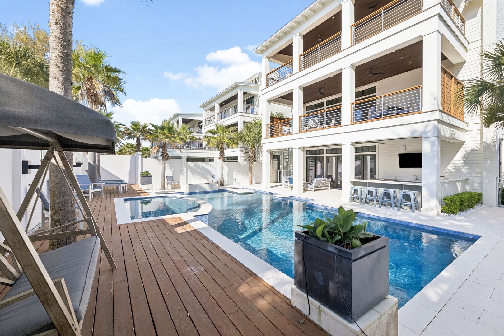 Modern luxury villa featuring a stunning pool with tropical palm trees and contemporary architecture.