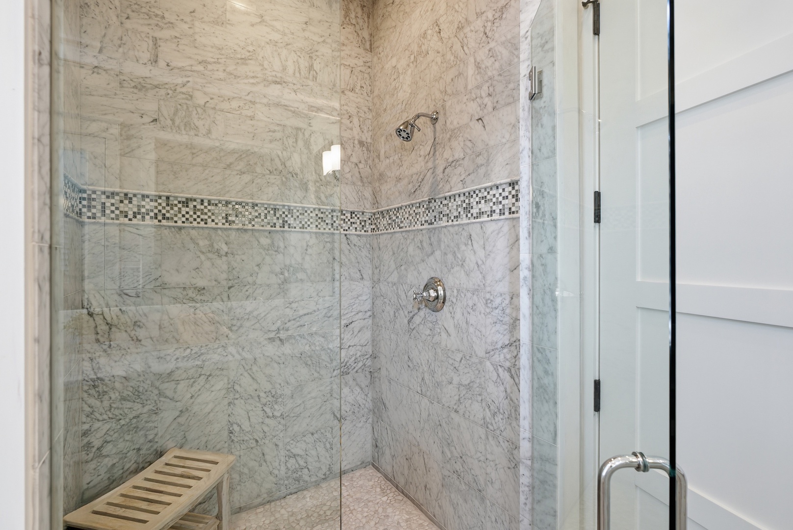 Step into a spacious walk-in shower adorned with elegant marble tile and a decorative mosaic accent band. The glass enclosure and modern fixtures create a luxurious, spa-like retreat.