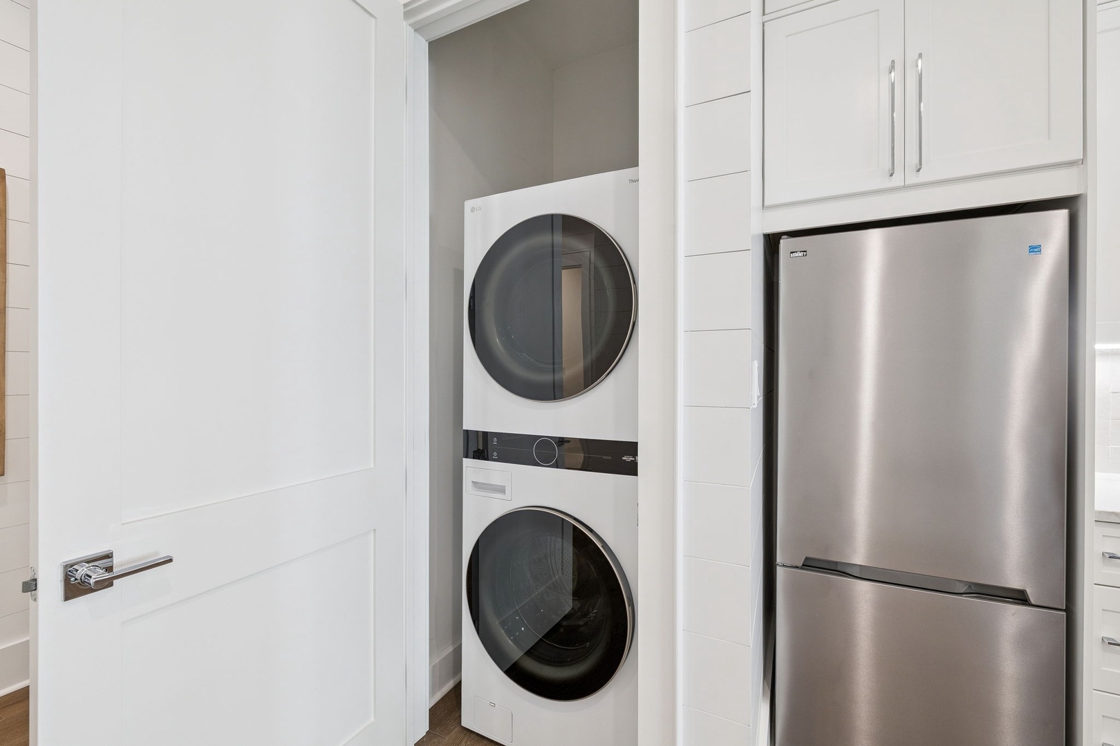 Your laundry stays fresh with convenient stacked washer and dryer tucked neatly into sleek white cabinetry.