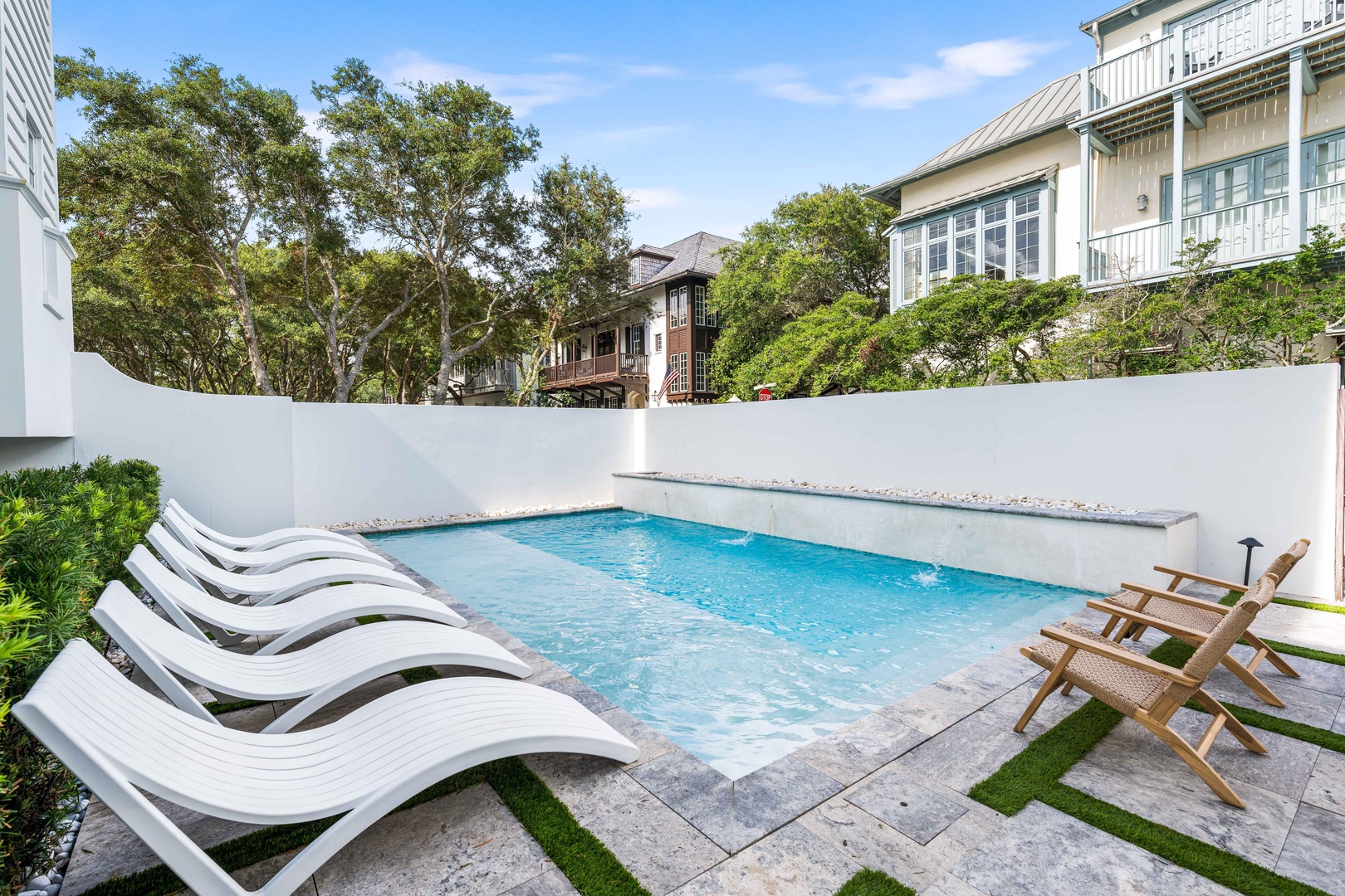 Your private pool oasis awaits with sleek lounge chairs and teak dining furniture, perfectly positioned for sunny afternoons and peaceful evenings.