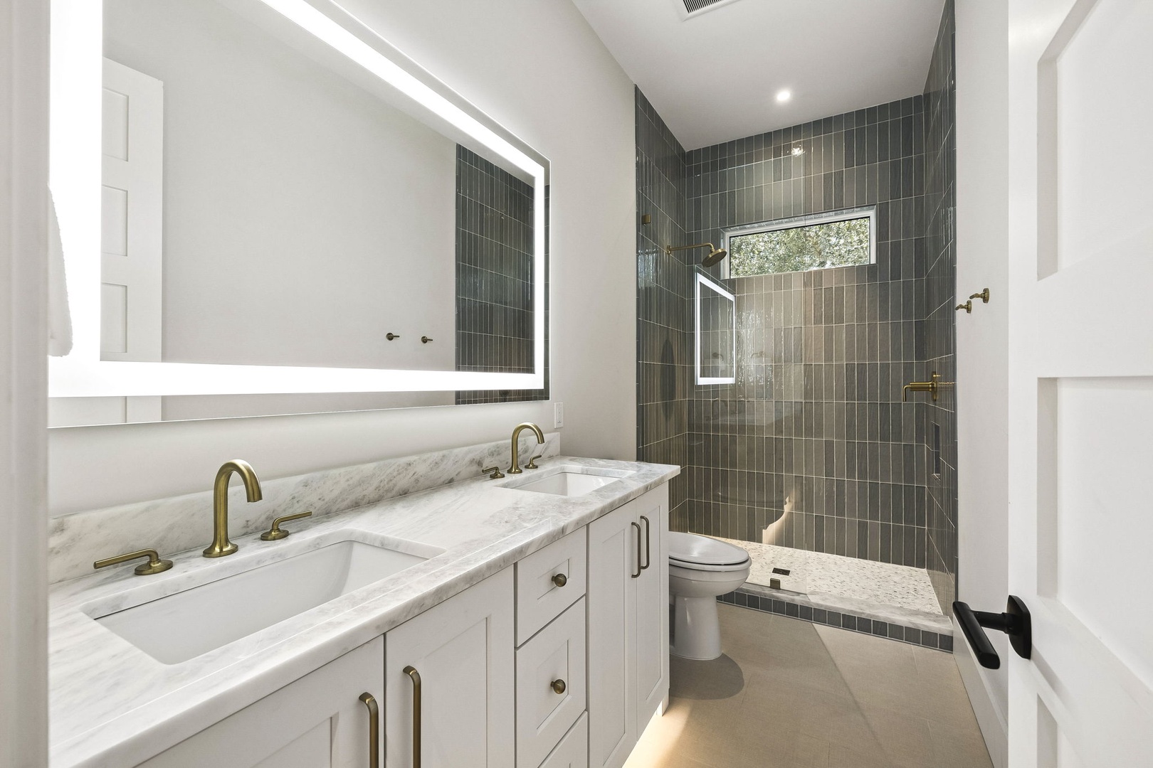 Step into this elegant bathroom where pristine marble countertops meet sophisticated tiled surfaces. Your morning routine feels luxurious with dual sinks and a spa-like walk-in shower awaiting you.