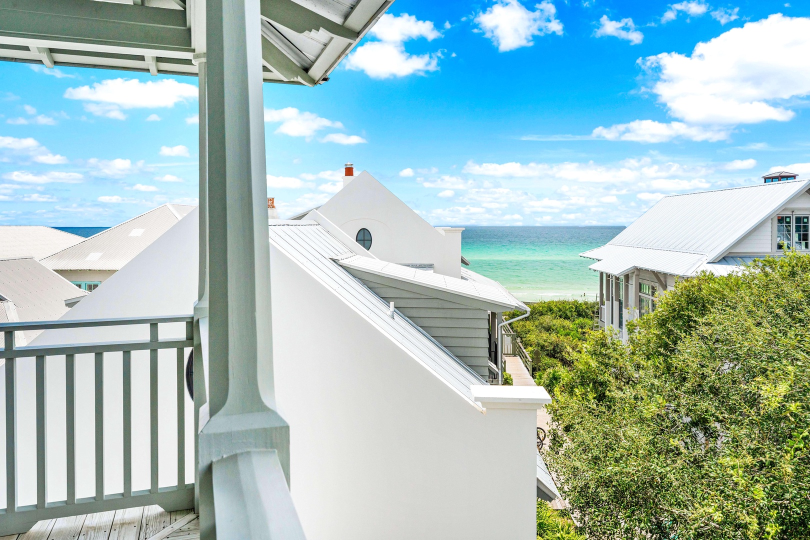 Covered balcony with stunning ocean views overlooking coastal rooftops and emerald waters.
