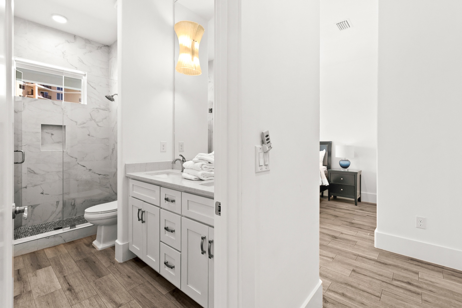 Step into your pristine ensuite with elegant marble-look tile, a refreshing walk-in shower, and a bright vanity with plush towels waiting for you. Sleek modern fixtures and thoughtful storage make it easy to settle in and unwind.