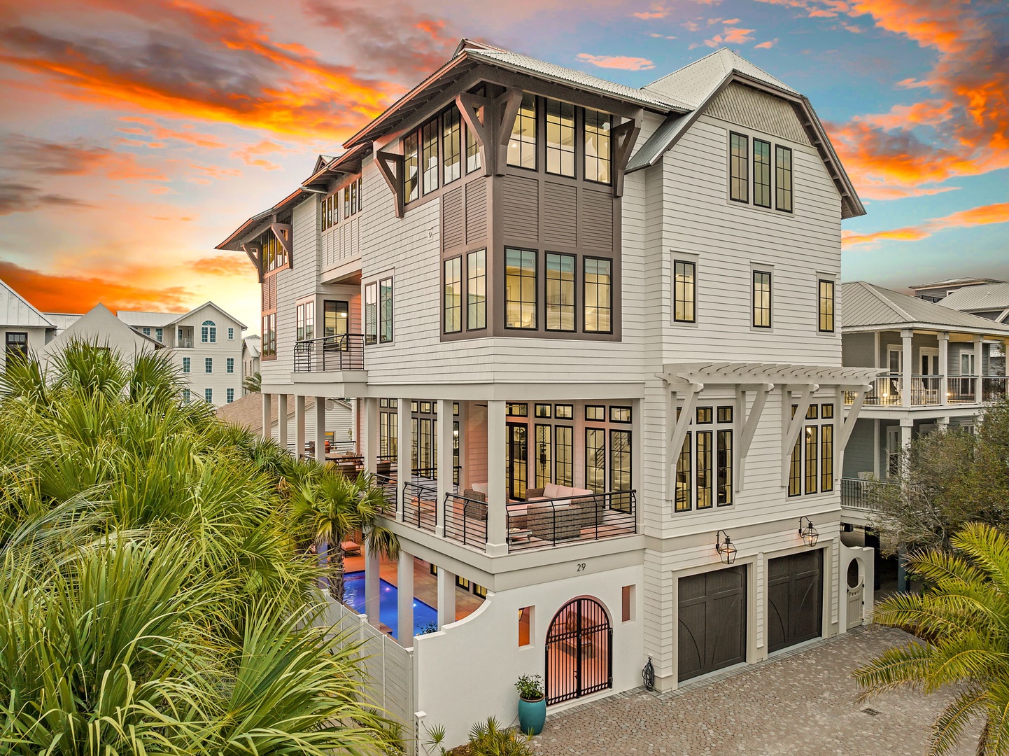 Stunning coastal property with elegant architecture and tropical landscaping, set against a breathtaking sunset sky in a peaceful neighborhood.