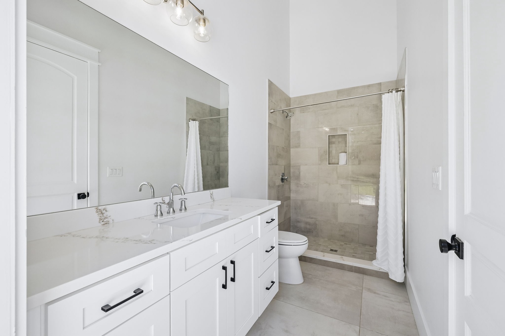 Step into your pristine private bathroom with elegant marble countertops, modern fixtures, and a spacious walk-in shower designed for your relaxation and comfort.