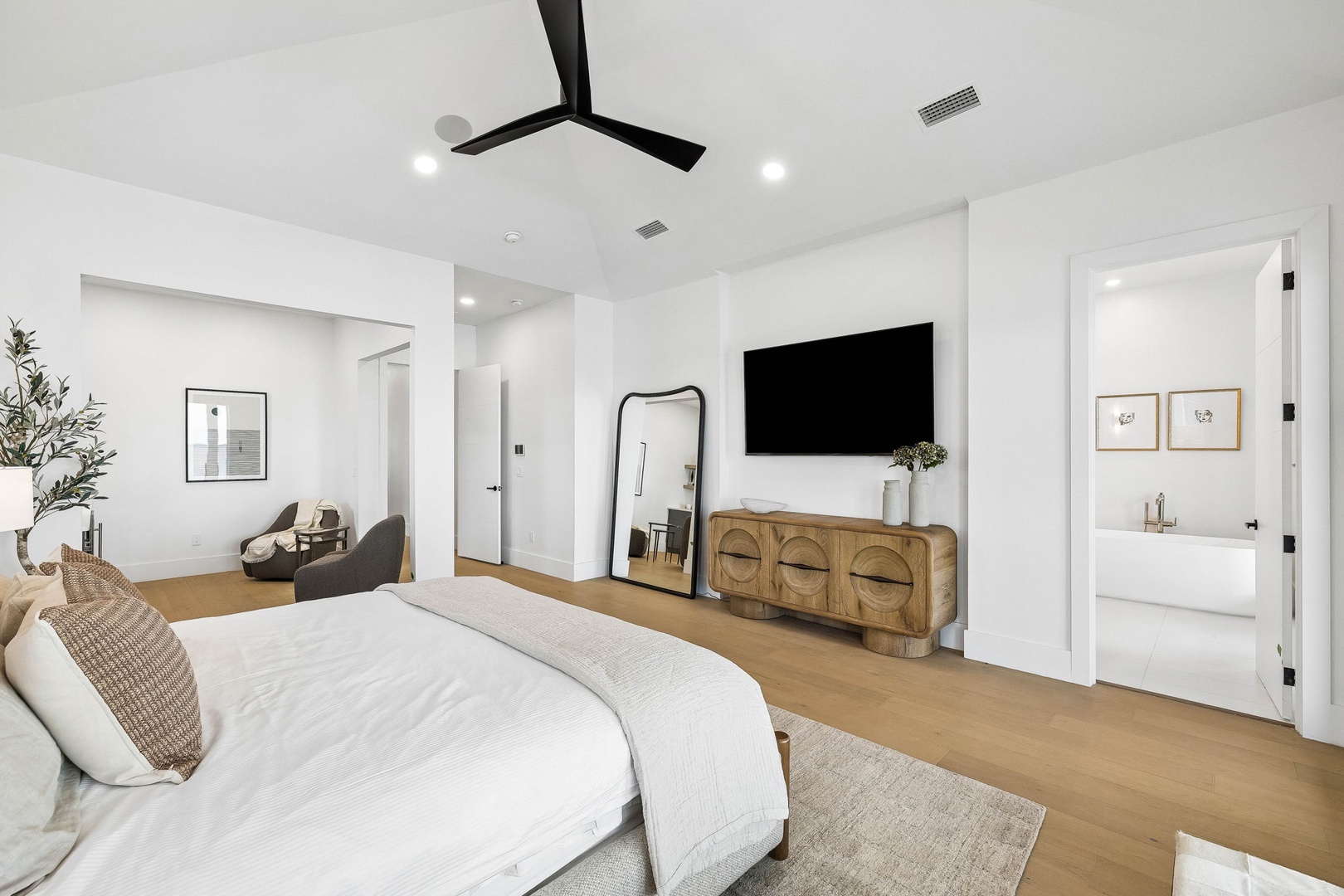 Slip into crisp white linens in your serene bedroom, where modern comfort meets coastal charm. A stylish ceiling fan keeps things cool as you relax in your peaceful retreat.