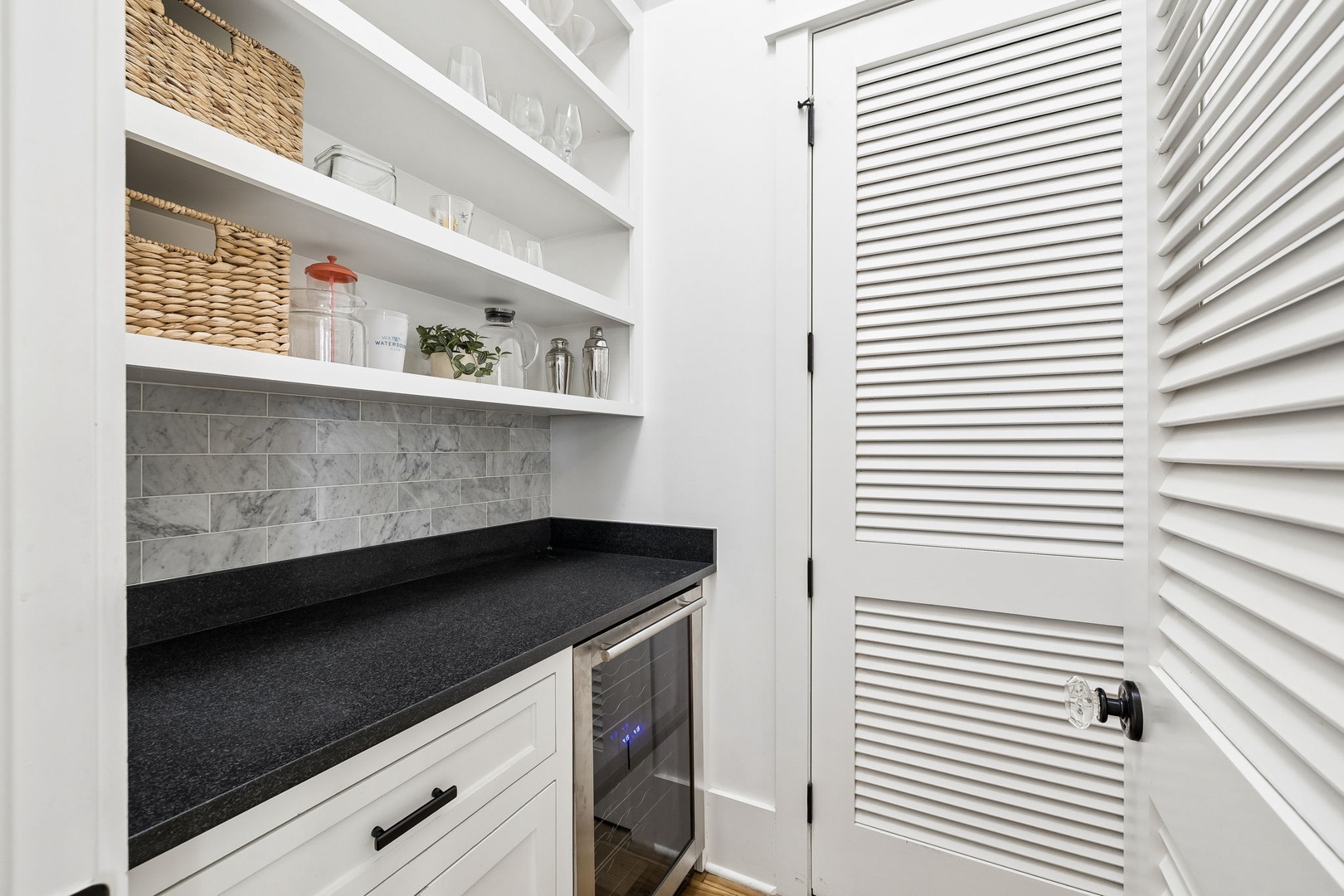 Your own butler's pantry features open shelving, a mini fridge, and elegant marble tilework—perfect for storing snacks, chilling drinks, or prepping morning coffee in style.