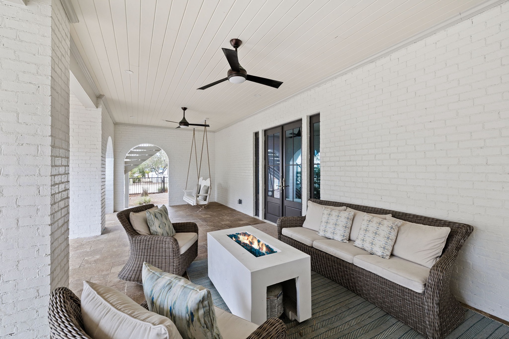 Sink into plush wicker seating on your covered patio, where the modern fire table creates warmth while ceiling fans keep you cool.