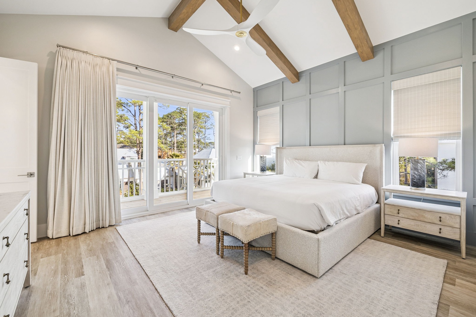 Unwind in your serene bedroom sanctuary with soaring ceilings, warm wood beams, and peaceful tree views from your private balcony.