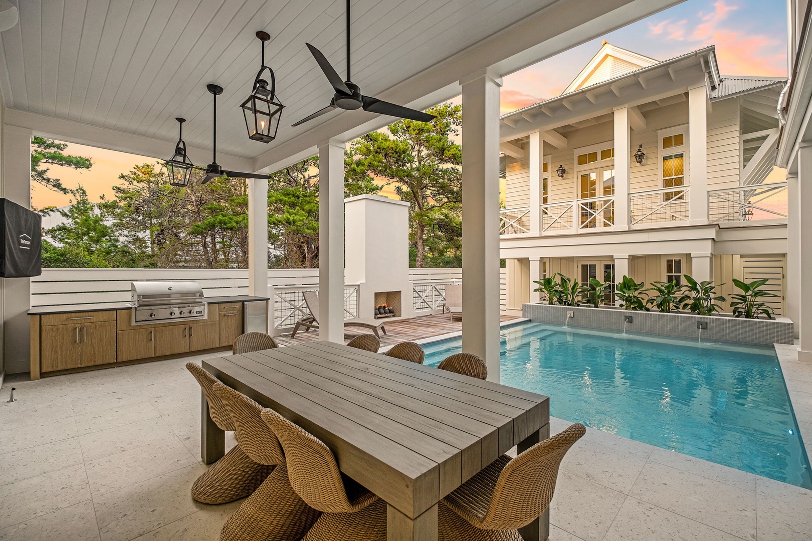 A covered patio dining area with grill faces the sparkling pool, perfect for your group meals and sunset gatherings.
